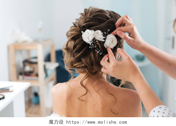美发师正在给一位新娘盘头发理发师给新娘做了一个优雅的发型，头发上插着白花
